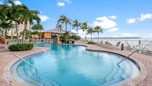 A swimming pool with a 3 FT 3 IN depth marker, surrounded by palm trees and a view of the water.