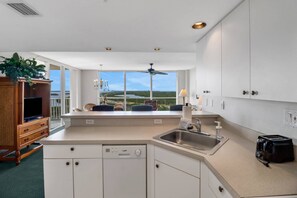 Een moderne keuken met een groot eiland, een ingebouwde vaatwasser en uitzicht op het buitengebied.