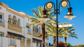 Street lamps, a street sign, and a building with balconies and palm trees.