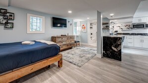 A modern bedroom with a wooden bed, a dresser, and a TV on the wall. - Chic & Spacious Bi-Level Bucktown Condo - Sleeps 8 (Chicago)