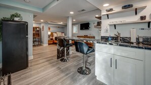 A modern kitchen with a marble countertop, white cabinets, and a black refrigerator. - Chic & Spacious Bi-Level Bucktown Condo - Sleeps 8 (Chicago)