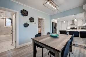 Una cucina moderna con mobili bianchi, elettrodomestici in acciaio inossidabile e luci a sospensione.