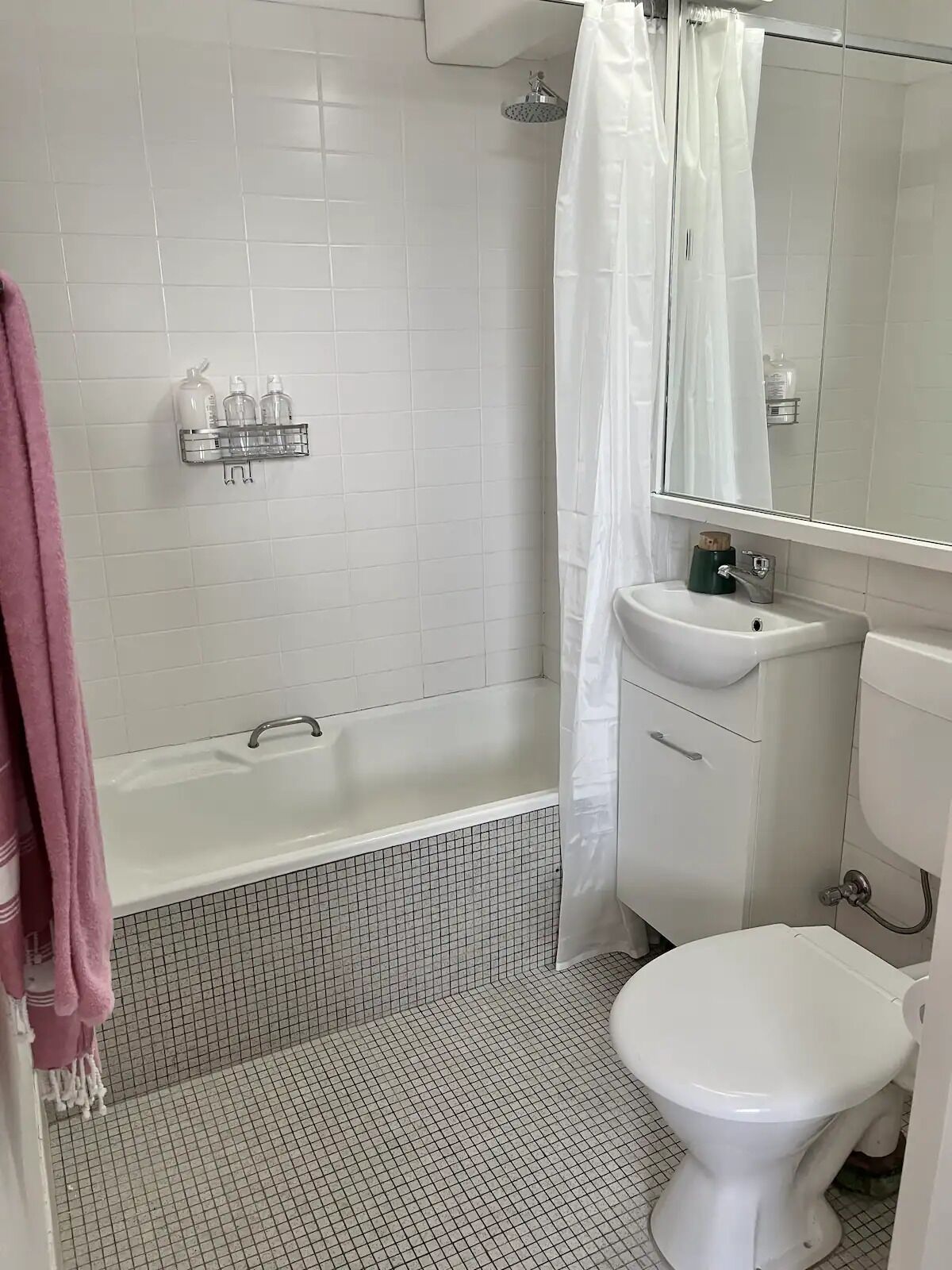 Un baño con una bañera blanca, un inodoro blanco y un lavamanos con espejo.