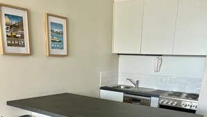 A kitchen with a central island, bar stools, a stove, and a sink. - Beachfront Living, Manly Beach, Sydney (Manly)