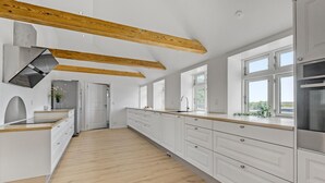A modern kitchen with white cabinetry, wooden beams, a stainless steel refrigerator, and a large window offering a view. - Nice home in Janderup Vestj with sauna (Janderup Vestj)
