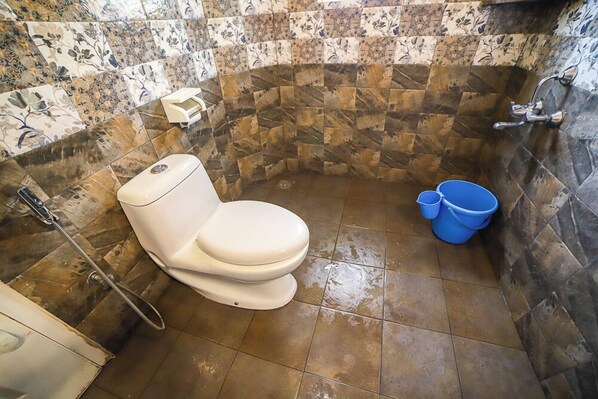 A bathroom with a toilet, shower, and blue buckets. - Samrakshitha - The Villa (Kotagiri)