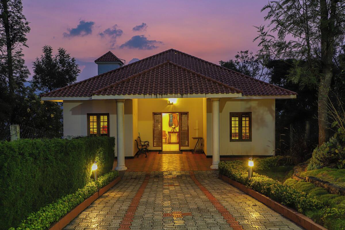 A house with a tiled roof, a porch, and a pathway leading to the entrance.