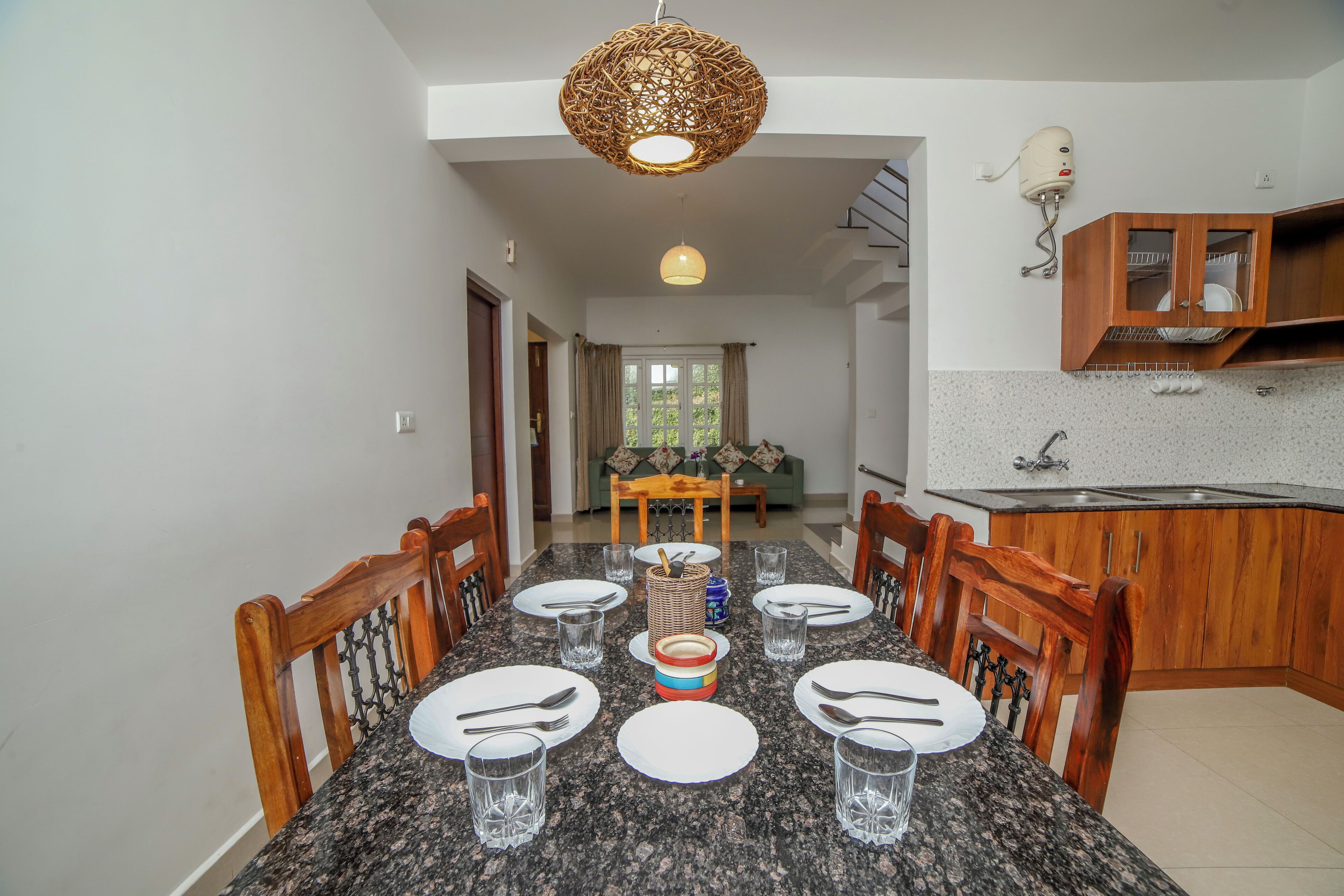 A dining area with a granite table, wooden chairs, and a hanging light fixture.