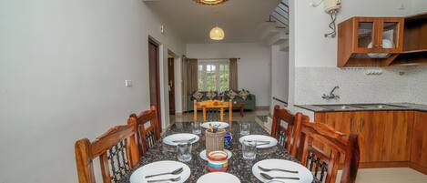 A dining area with a granite table, wooden chairs, and a hanging light fixture.
