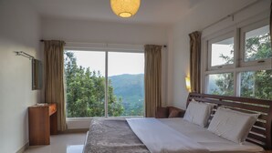 Ένα υπνοδωμάτιο με ένα μεγάλο κρεβάτι, ένα κομοδίνο, μια ξύλινη συρταριέρα και ένα παράθυρο με κουρτίνες.
