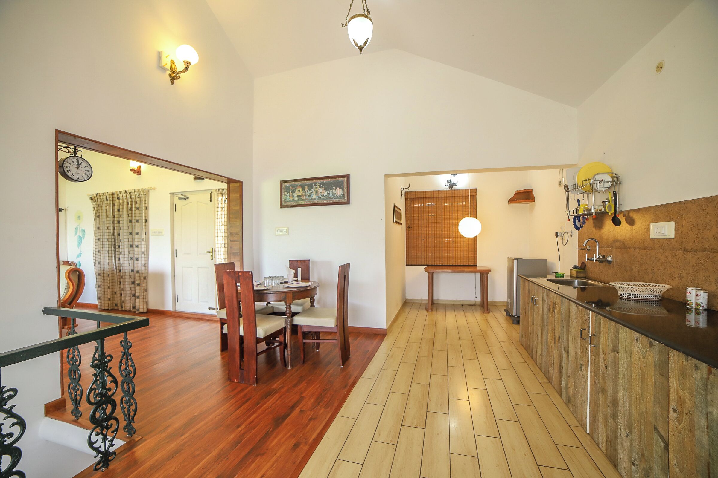 A spacious kitchen with wooden flooring, a dining area with a wooden table and chairs, and a kitchen counter with a sink and various appliances.