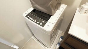 A compact, modern washing machine with a control panel and a grey laundry basket on top. - Skytree & Asakusa in front! Newly built clean apt! (墨田区)