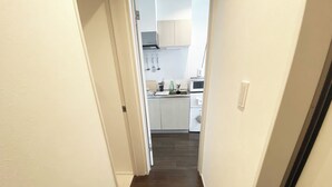 A hallway with a welcome mat leading to a kitchen area. - Skytree & Asakusa in front! Newly built clean apt! (墨田区)