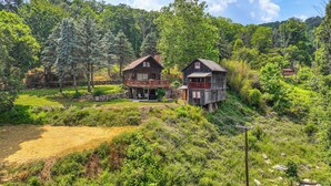 A rustic cabin with a balcony, surrounded by lush greenery and a clear sky. - Cozy Luray Cabin w/ Views: Near Hiking Trails! (Luray)