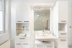 A modern bathroom with a white sink, mirror, and storage cabinets. - Apartment 'Am Goldenen Löwen' with Private Terrace, Garden, and Wi-Fi (Bobritzsch-Hilbersdorf)