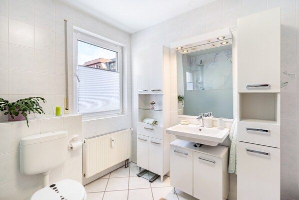 Un baño moderno con inodoro, lavamanos y espejo.