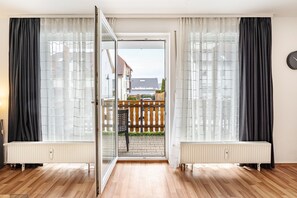 Una habitación con una puerta corredera de vidrio que da a un patio exterior, un radiador y un reloj en la pared.
