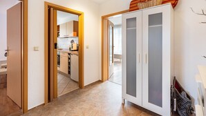 Un couloir avec un placard, une porte donnant sur la cuisine et un panier accroché au mur.