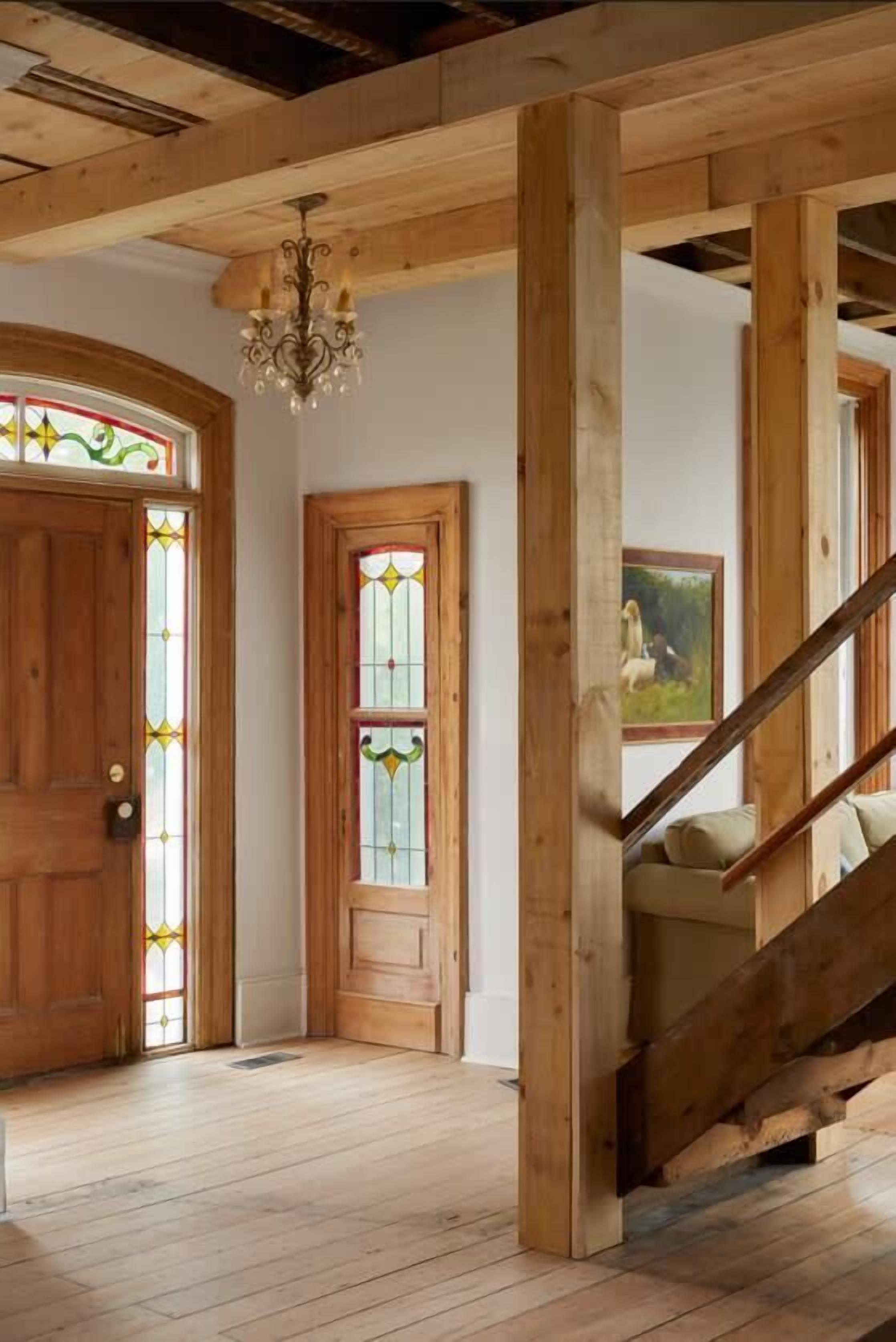 Interior de madera con escalera, vigas de madera y una araña.