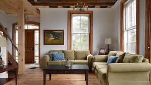 A cozy living room with two sofas, a coffee table, and a painting on the wall. - 5 Bdrm w/ private beach amazing lake views (Prince Edward)