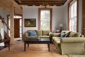 A cozy living room with two sofas, a coffee table, and a painting on the wall. - 5 Bdrm w/ private beach amazing lake views (Prince Edward)