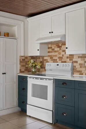 A kitchen with white cabinets, a white stove, and a tiled backsplash. - 5 Bdrm w/ private beach amazing lake views (Prince Edward)