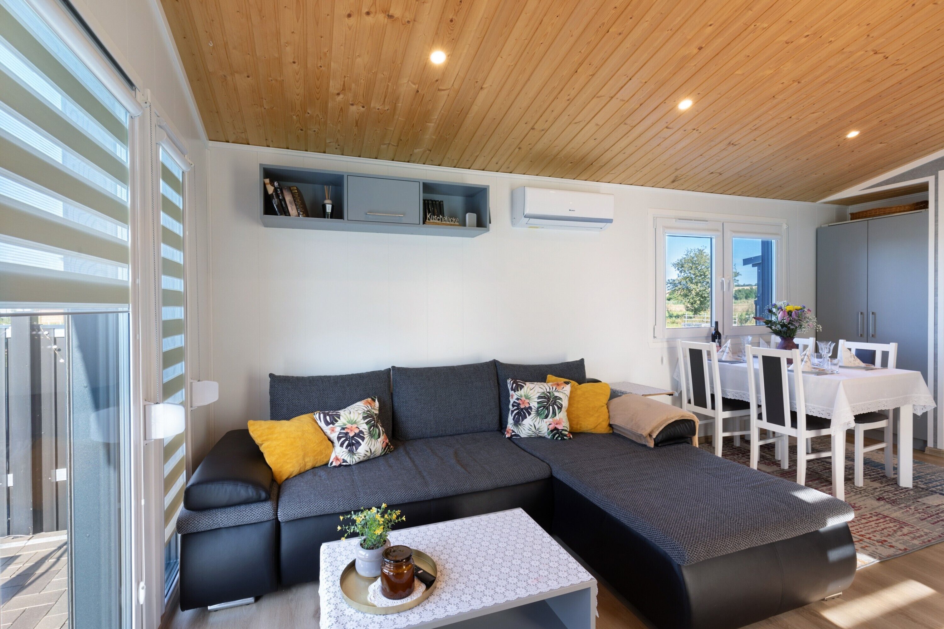 A modern living room with a sectional sofa, a dining table, and a small coffee table.