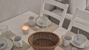 A dining table set with plates, bowls, cups, and a candle. - Apartment Eschenweg incl. balcony with garden view, bed linen and towels (Bad Harzburg)