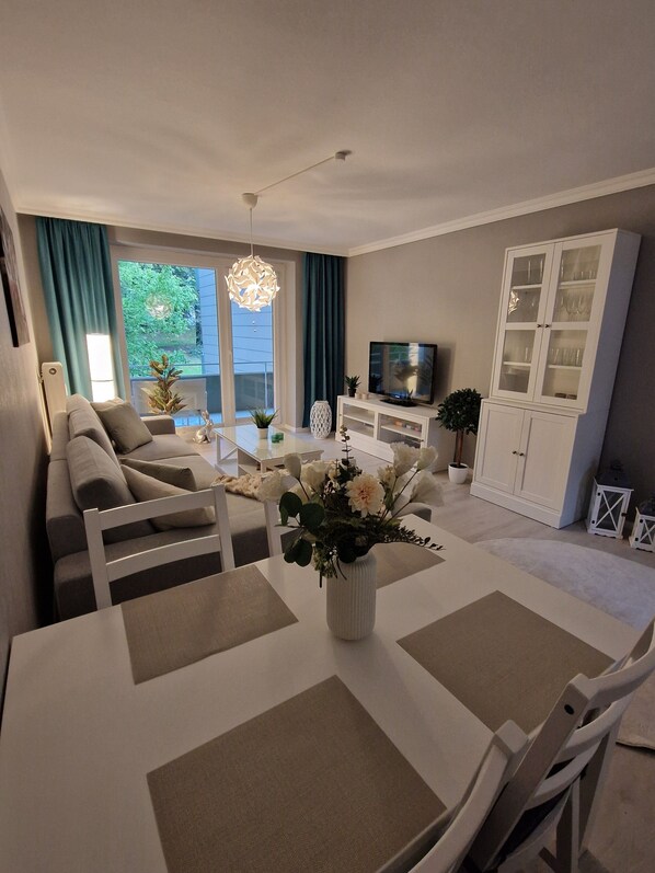 A modern living room with a sofa, dining table, TV, and a cabinet.
