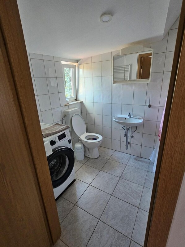 A compact bathroom with a toilet, sink, and washing machine.