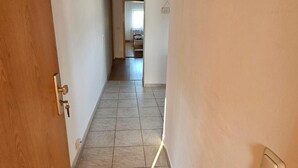 A hallway with a wooden door on the left, a light switch on the right, and a tiled floor. - Apartment 'Ferienwohnung Peter' (Rudolstadt)