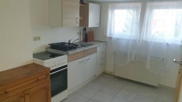 A kitchen with a stove, oven, sink, and cabinets.