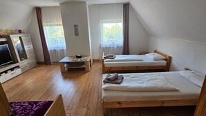 A room with two wooden beds, a TV, a small table, and a dresser. - Apartment 'Ferienwohnung Peter' (Rudolstadt)