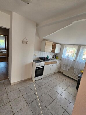 A kitchen with white cabinets, a stove, and a tiled floor.