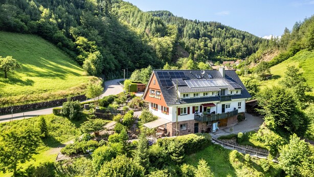 A house with solar panels, surrounded by lush greenery and hills. - Apartment 'Ferienwohnung 1 Talblick' with Mountain View, Shared Terrace and Wi-Fi (Oppenau)