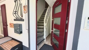 A red door leading to a staircase, a mailbox, and a bench outside. - Apartment 'Ferienwohnung 1 Talblick' with Mountain View, Shared Terrace and Wi-Fi (Oppenau)