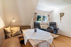 A room with a sofa, two chairs, a table, a lamp, and a window with curtains.