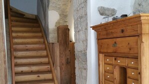 Eine Treppe führt zu einem Erkerbereich mit Steinwänden und Holzmöbeln.