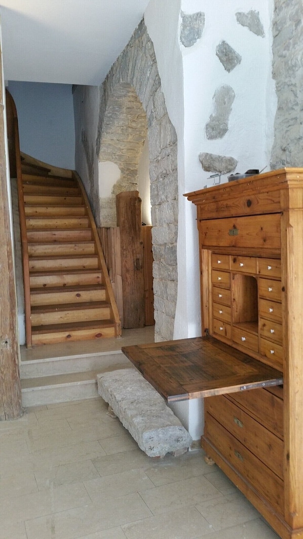 A staircase leading to a loft area with stone walls and wooden furniture.