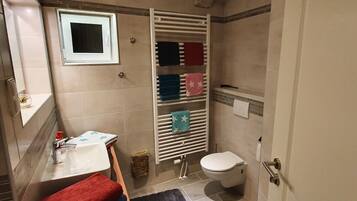 Une salle de bain équipée d’un lavabo, de toilettes, d’une douche et d’un porte-serviettes avec plusieurs serviettes.
