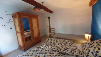 Ein Schlafzimmer mit einem Holzschrank, einem Bett mit gemusterten Betttextilien, einem Sessel und einer Wand mit einem Textauszug.
