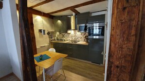 A compact kitchen with a wooden table, a white chair, and a microwave.