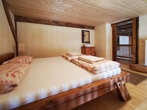 Un lit en bois avec une tête de lit, une table de chevet avec un miroir et un plancher en bois.