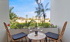 A balcony with a table, two chairs, a bottle of wine, and two glasses. - Zantamar 103C: ground floor Suite in La Cruz With parking lot (La Cruz de Huanacaxtle)