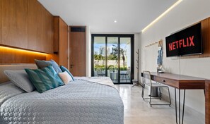 A modern bedroom with a large bed, a desk, and a TV displaying the Netflix logo. - Zantamar 103C: ground floor Suite in La Cruz With parking lot (La Cruz de Huanacaxtle)