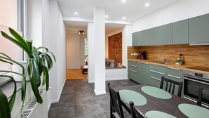 Een moderne keuken met groene kastjes, een houten aanrechtblad en een eethoek met een tafel en stoelen.