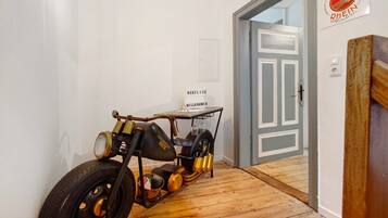 Ein altes Motorrad steht in einer Diele mit Holzboden und einer Tür zu einem weiteren Zimmer.