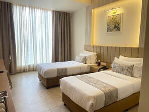 A hotel room with two beds, a desk, and a large window with curtains. - O'Nest Elite (Miraj)