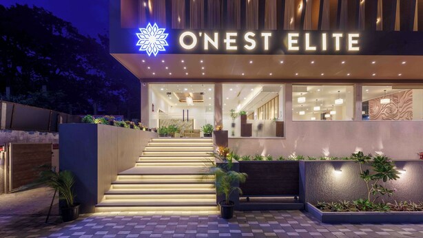 Ein moderner Hotelzugang mit einer Treppe zum Empfangsbereich, einem Schild mit der Aufschrift 'O'Nest Elite' und einer gut beleuchteten Fassade.