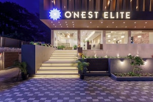 Una entrada de hotel moderna con una escalera que conduce al vestíbulo, un letrero que dice 'O'Nest Elite' y un exterior bien iluminado.